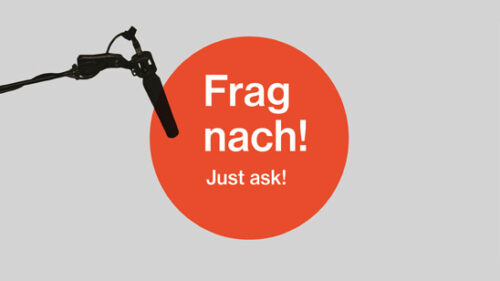 Graphic, red circle with the lettering "Frag nach, Just ask!", background grey"